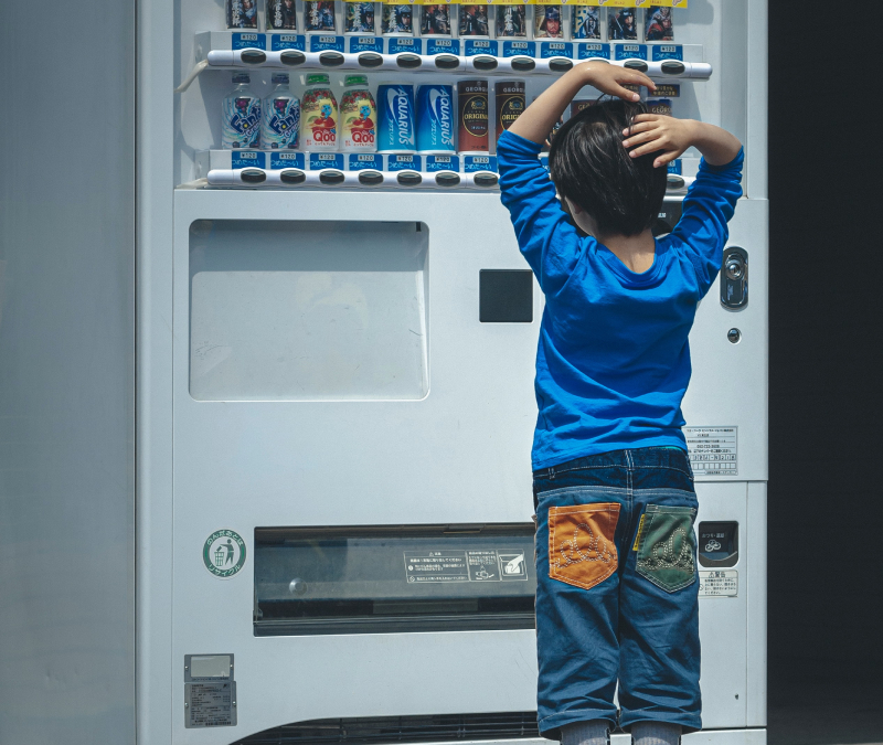 Pic of boy infront of vending machine in delimma which drink to choose