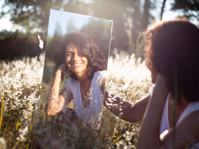 Pic of a girl holding mirror looking at SELF in the garden